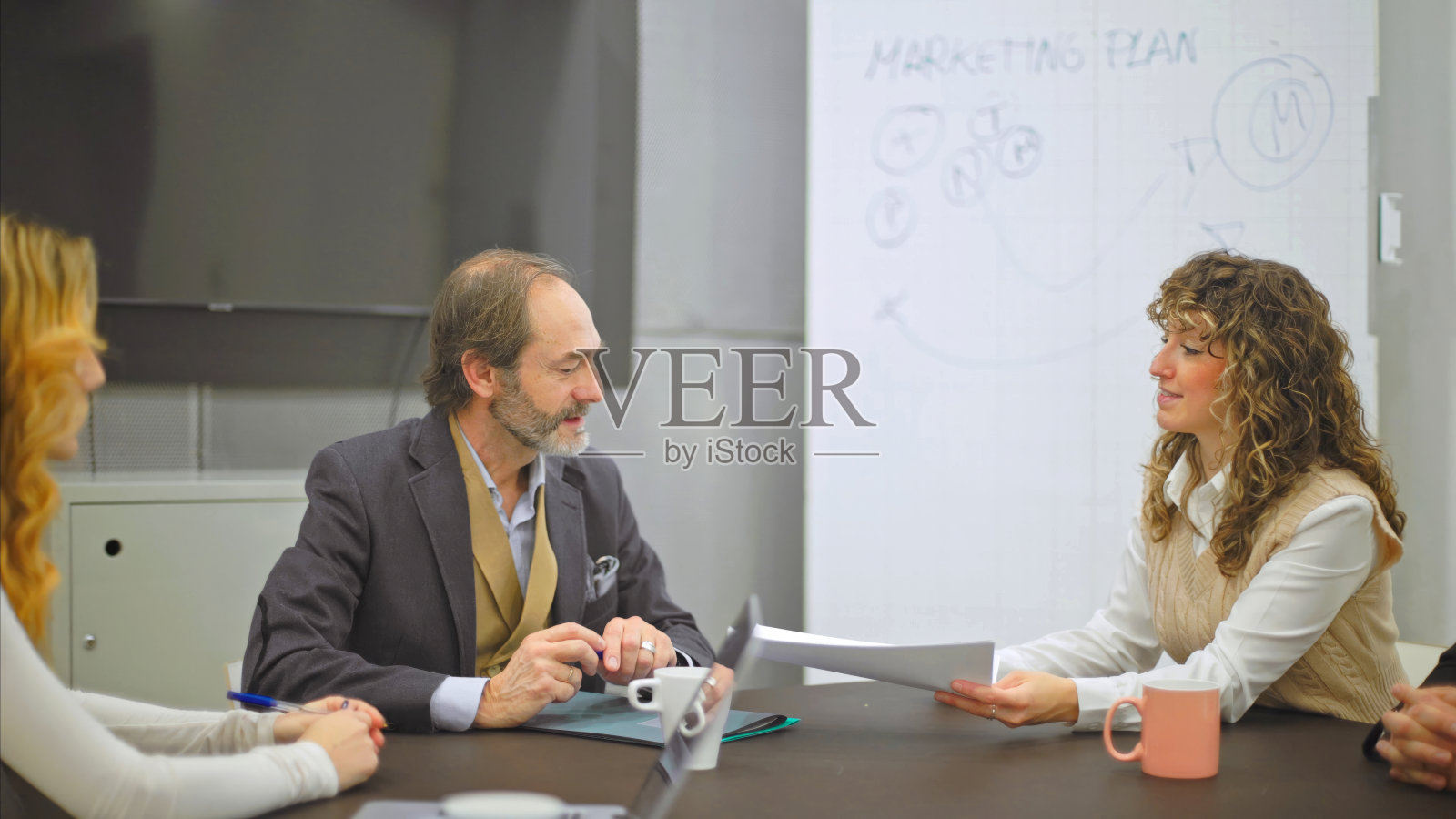 女商人在会议期间把文件递给同事。照片摄影图片