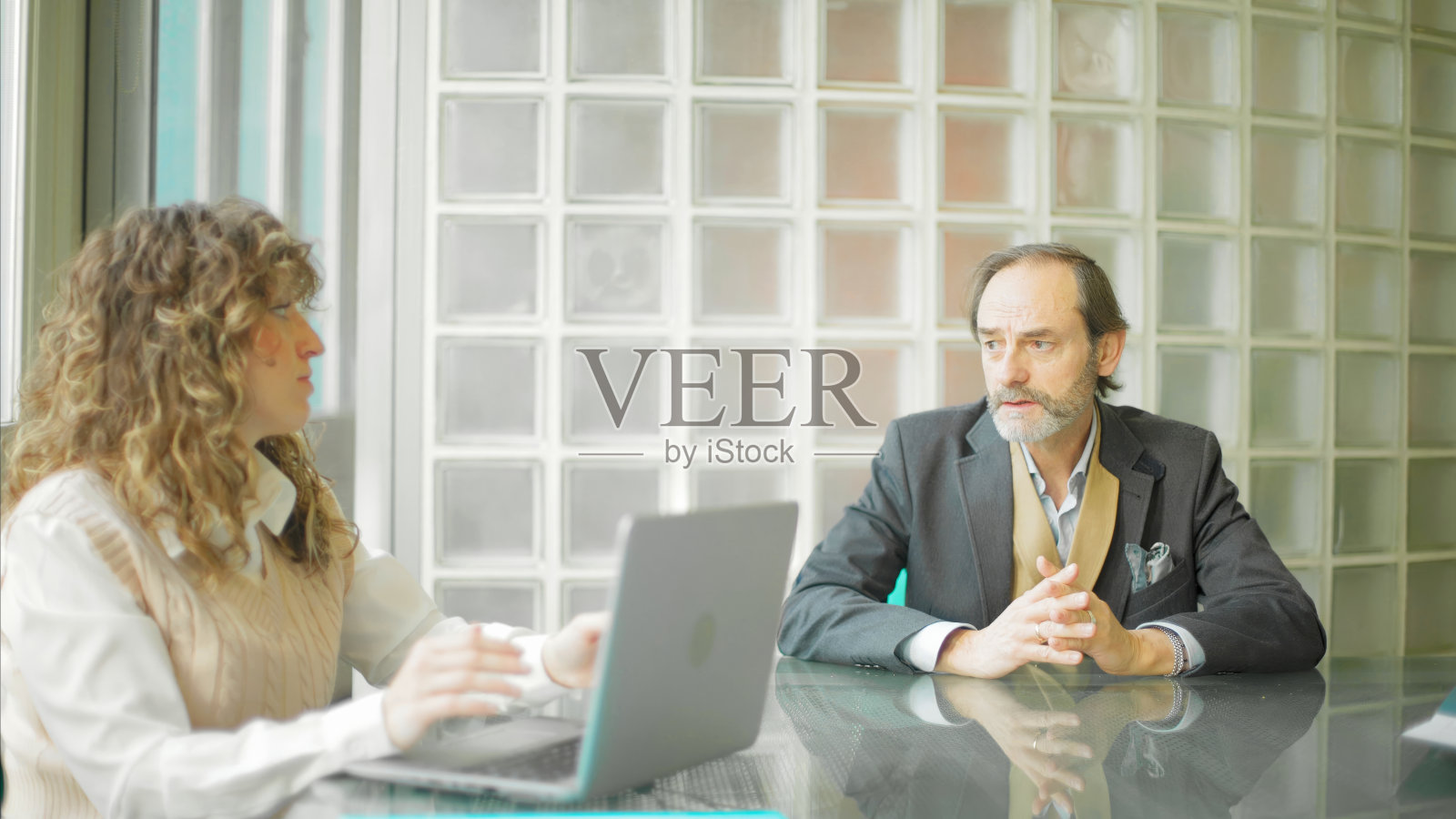 商业二人组在一次深思熟虑的讨论中被玻璃积木所吸引。照片摄影图片