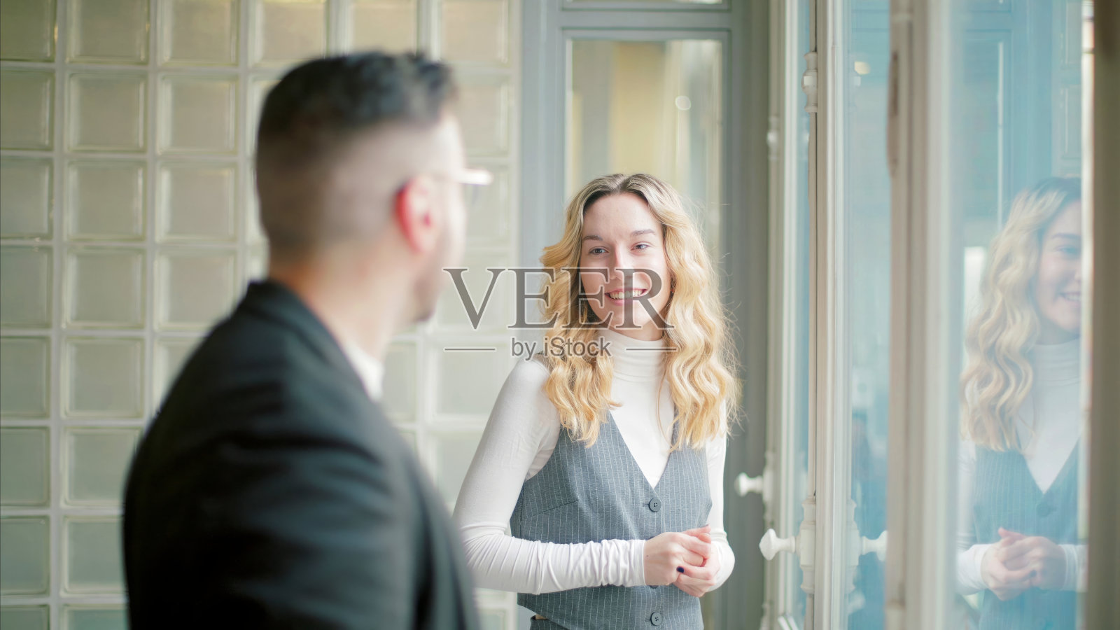 同事们隔着玻璃墙聊天照片摄影图片