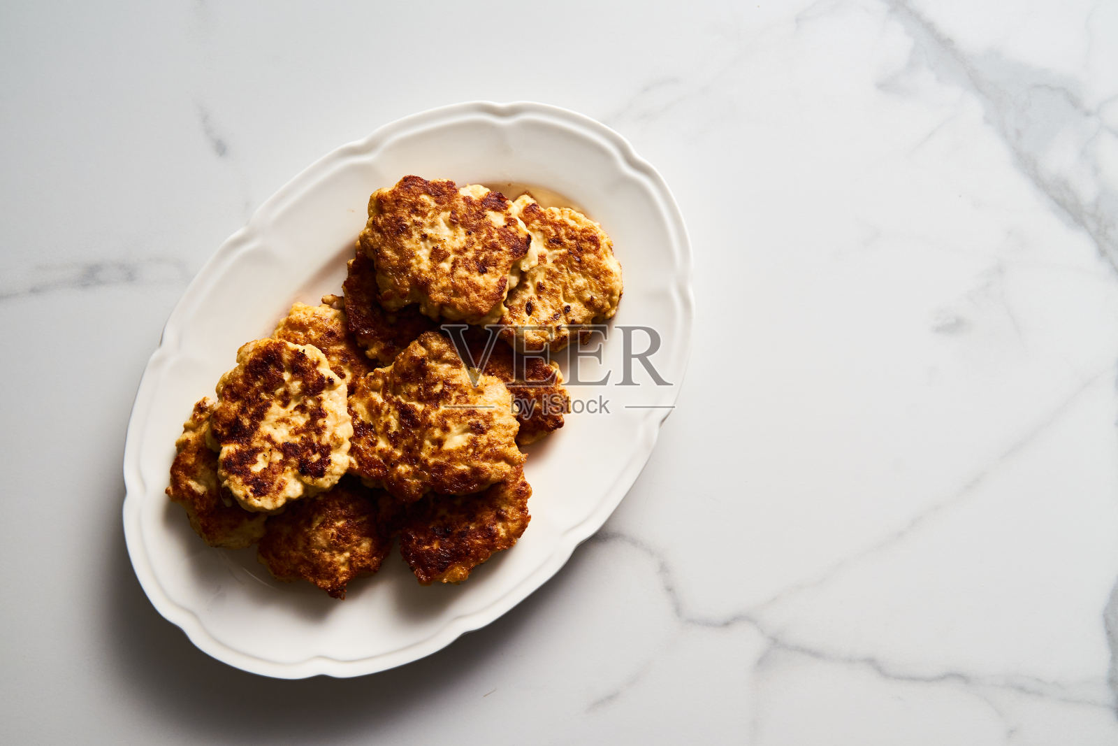 金黄色切碎的鸡肉肉片或配马苏里拉奶酪的肉饼，放在白色的复古盘子里。白色大理石背景上的极简主义食物照片照片摄影图片