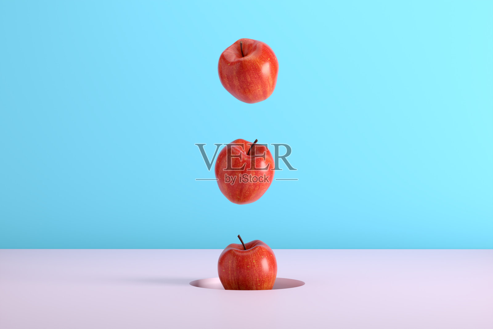 蓝色和粉红色的背景上，红苹果从一个洞里掉出来。照片摄影图片