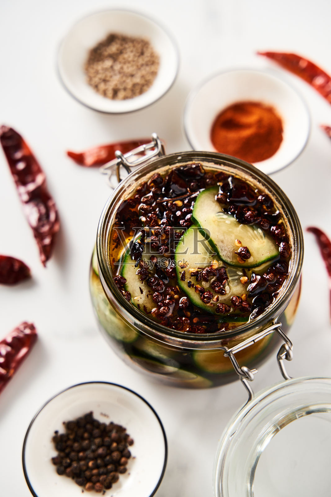 用亚洲或中国风味的罐子腌制黄瓜，加酱油、大蒜。还包括姜、辣椒和其他香料。白色大理石背景照片摄影图片