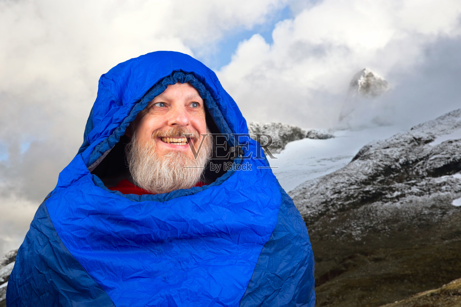 快乐的大胡子男子躺在睡袋里，身后是山间的自然风光。大自然在山间漫步照片摄影图片