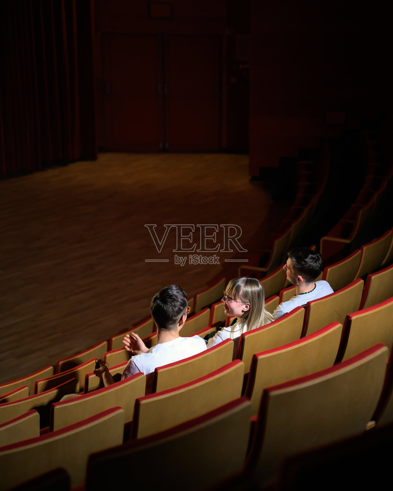 十几岁的女孩和两个男孩微笑着在电影院看电影照片摄影图片