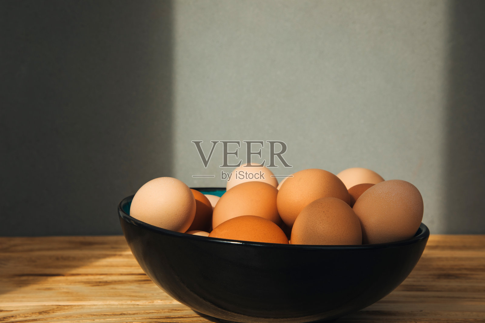 木桌上的一个大碗里盛着不同棕色和米色的鸡蛋。复活节的背景照片摄影图片