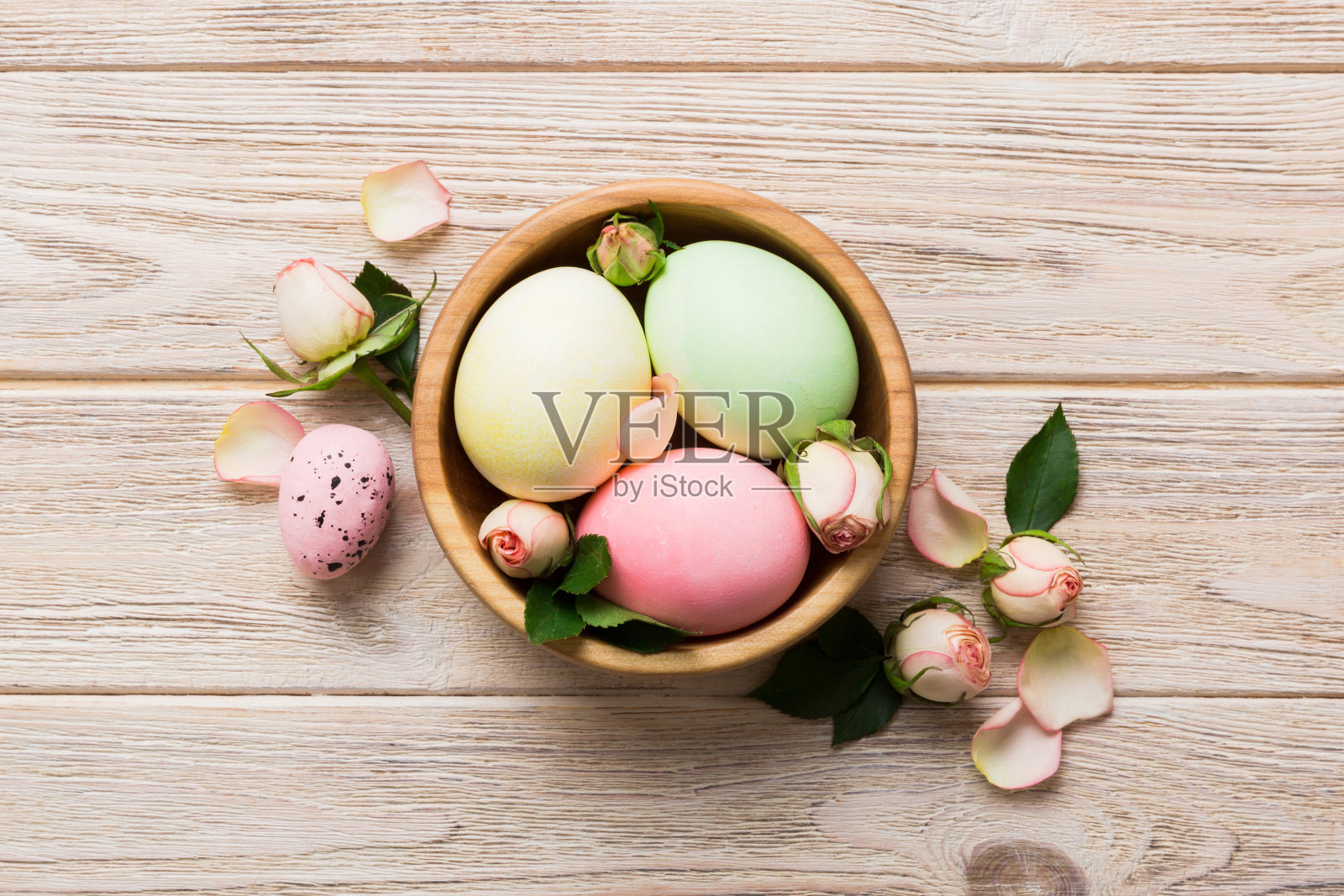 复活节快乐。复活节彩蛋放在篮子里，桌子上有黄玫瑰。自然染色彩色鸡蛋背景顶视图与复制空间照片摄影图片