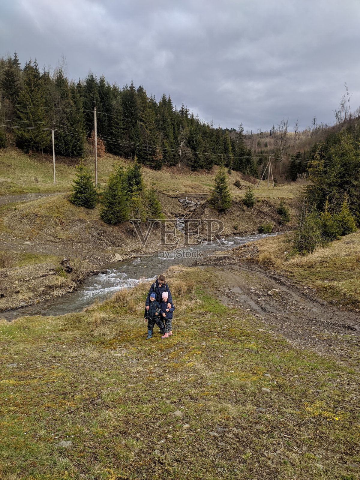 母亲带着孩子，以山坡为背景。照片。照片摄影图片