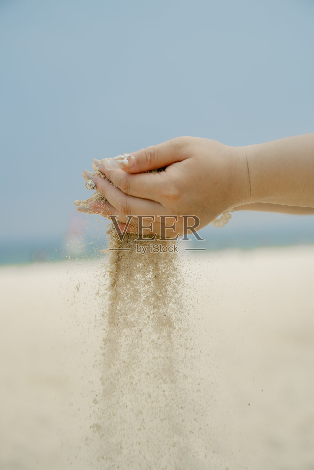在沙滩上，手里拿着沙粒照片摄影图片