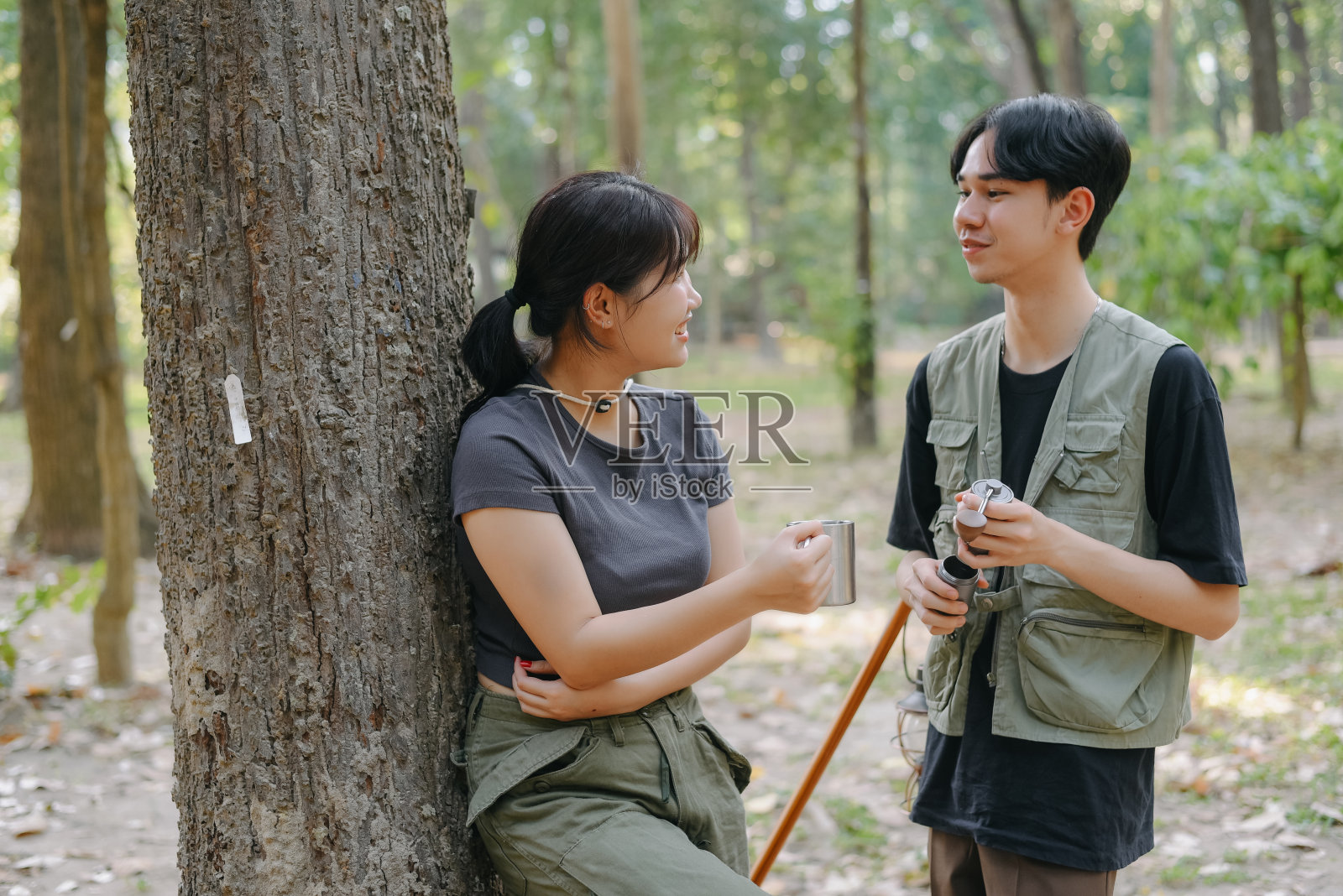 亚洲夫妇在营地边碰杯咖啡，在大自然中露营，他们感到放松和清爽。娱乐照片摄影图片