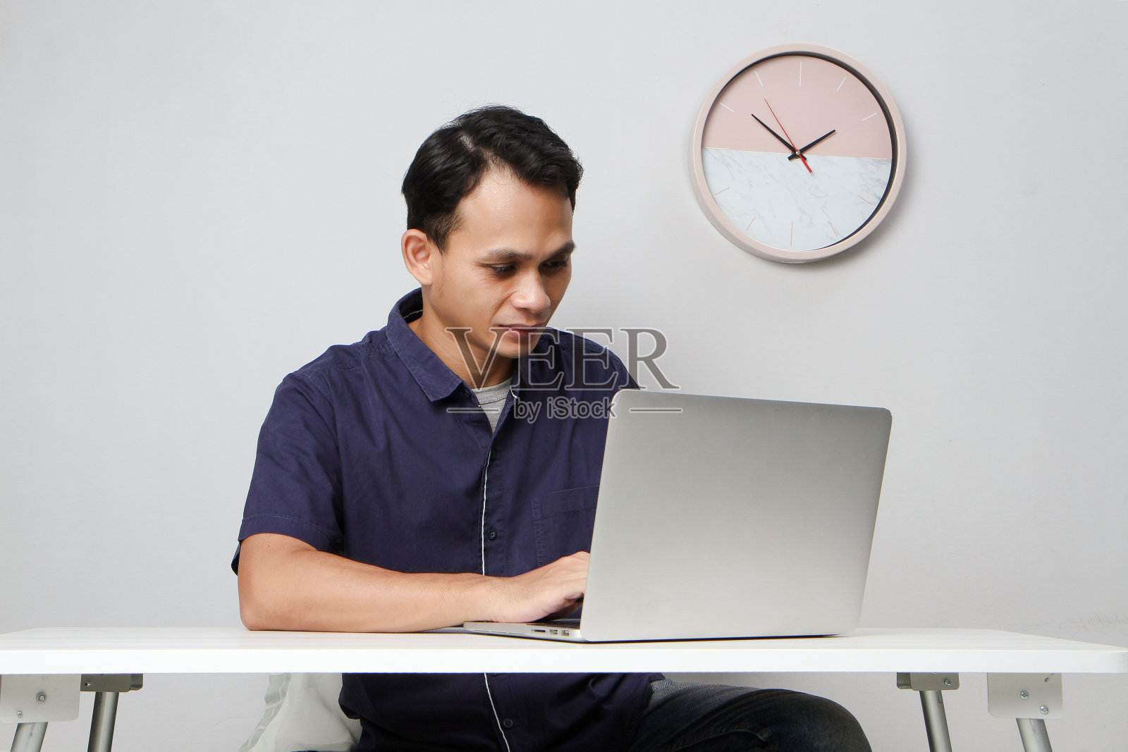 坐在笔记本电脑前的亚洲男人的专注的脸。在孤立的背景下照片摄影图片