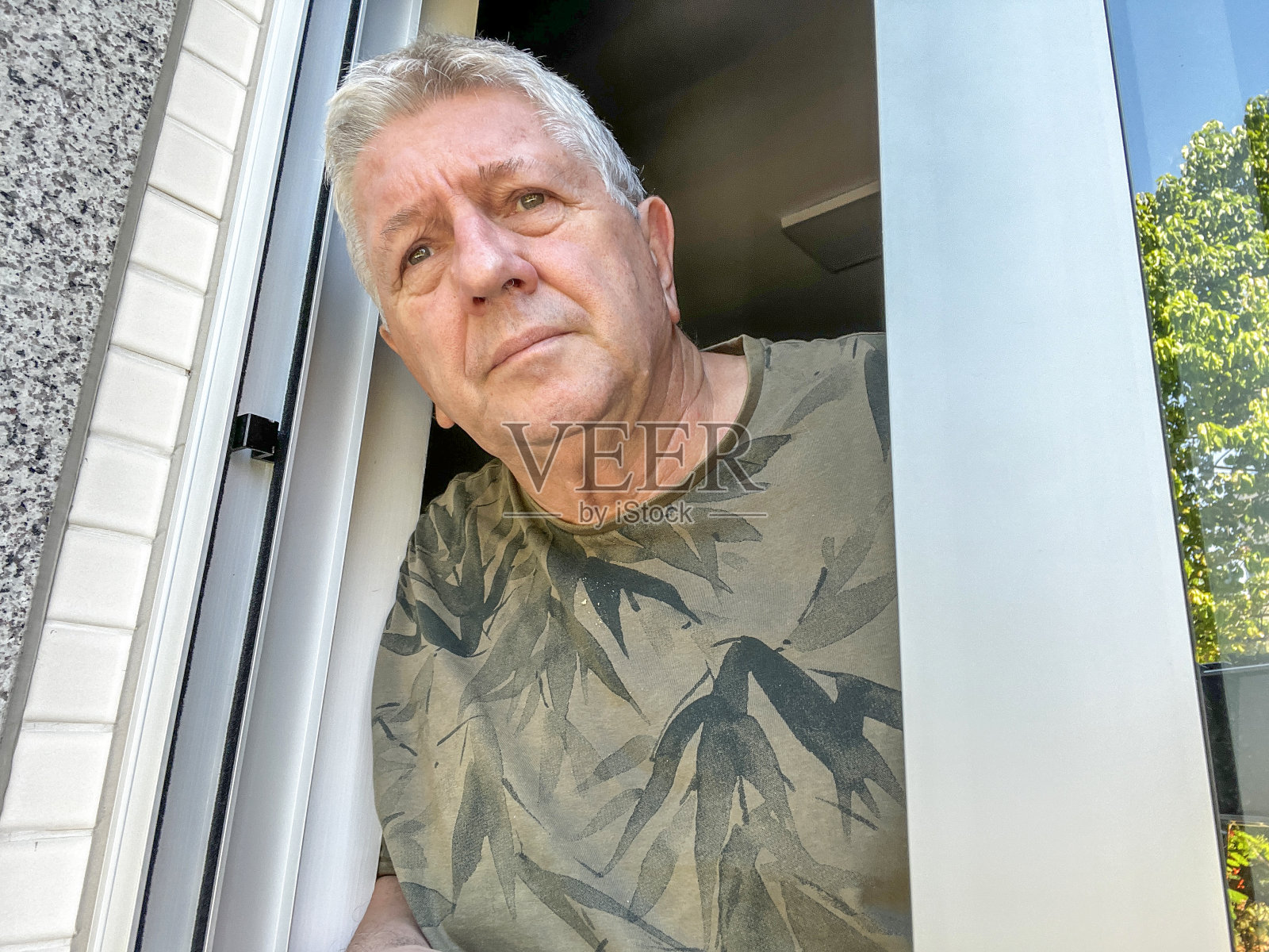 老年白人从公寓窗户往外看照片摄影图片