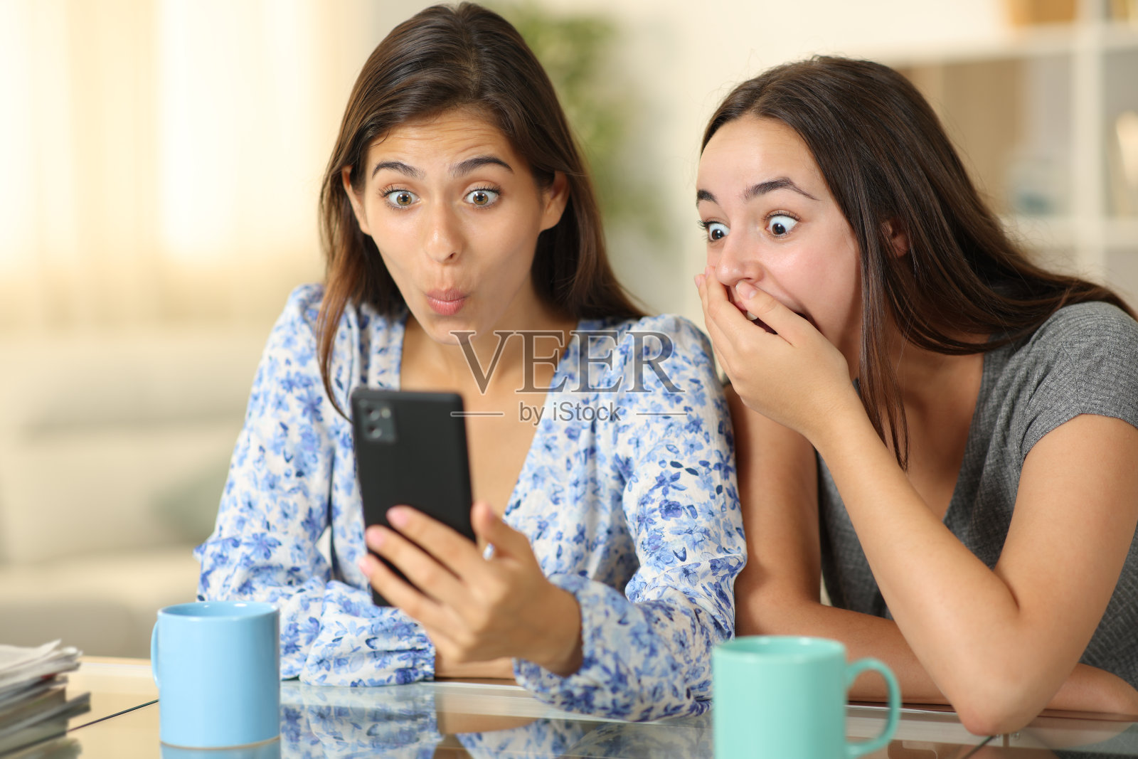 惊讶的女人在家里检查智能手机照片摄影图片