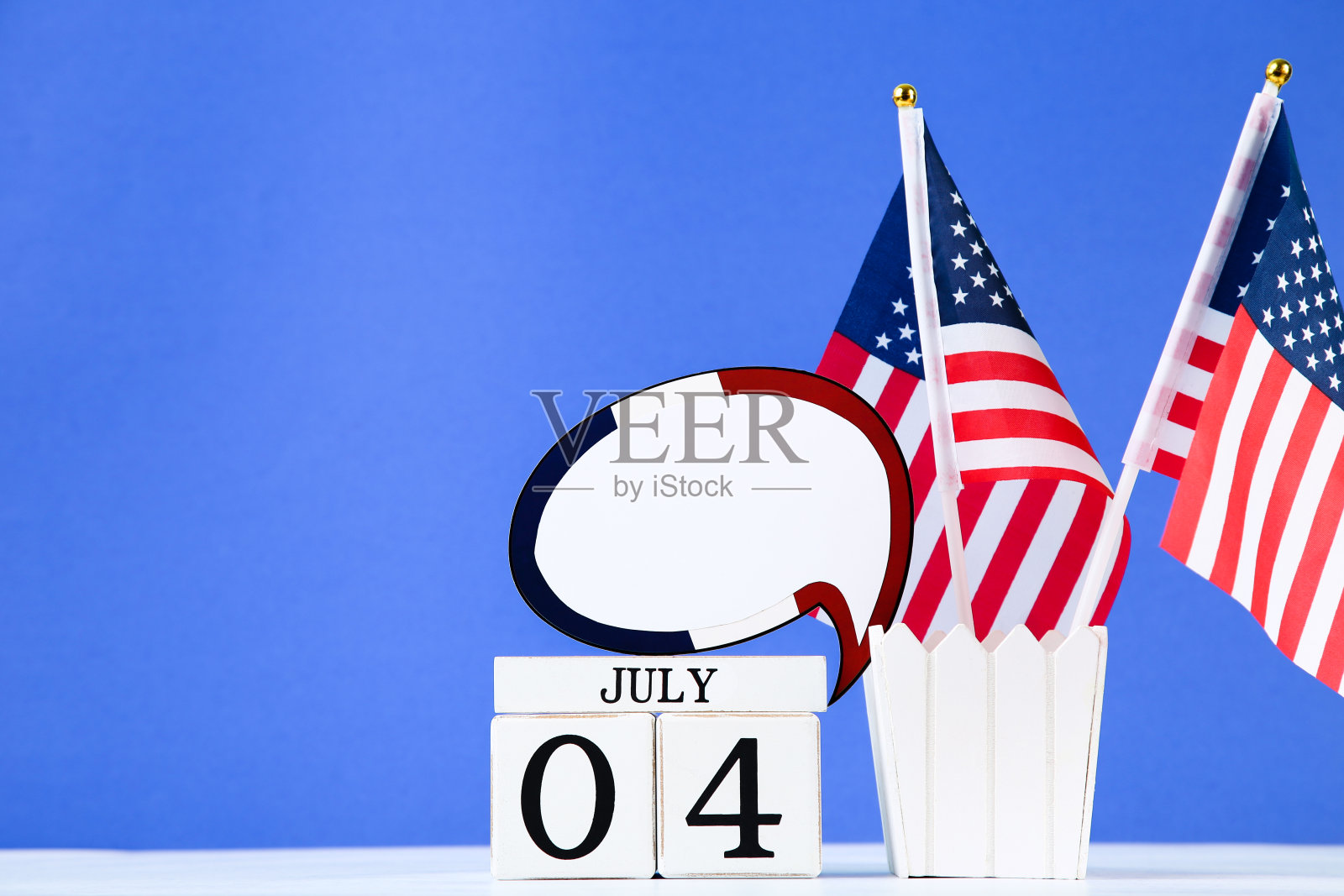 独立日的概念。美国国旗与立方体日历和空白的演讲气泡在蓝色背景照片摄影图片