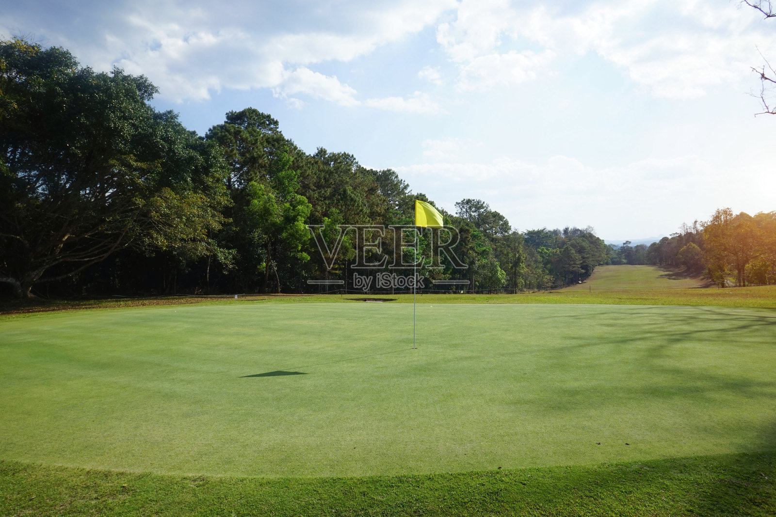 傍晚高尔夫球场的背景有阳光照耀在高尔夫球场在泰国。夏末的下午，高尔夫球场上的美景。照片摄影图片