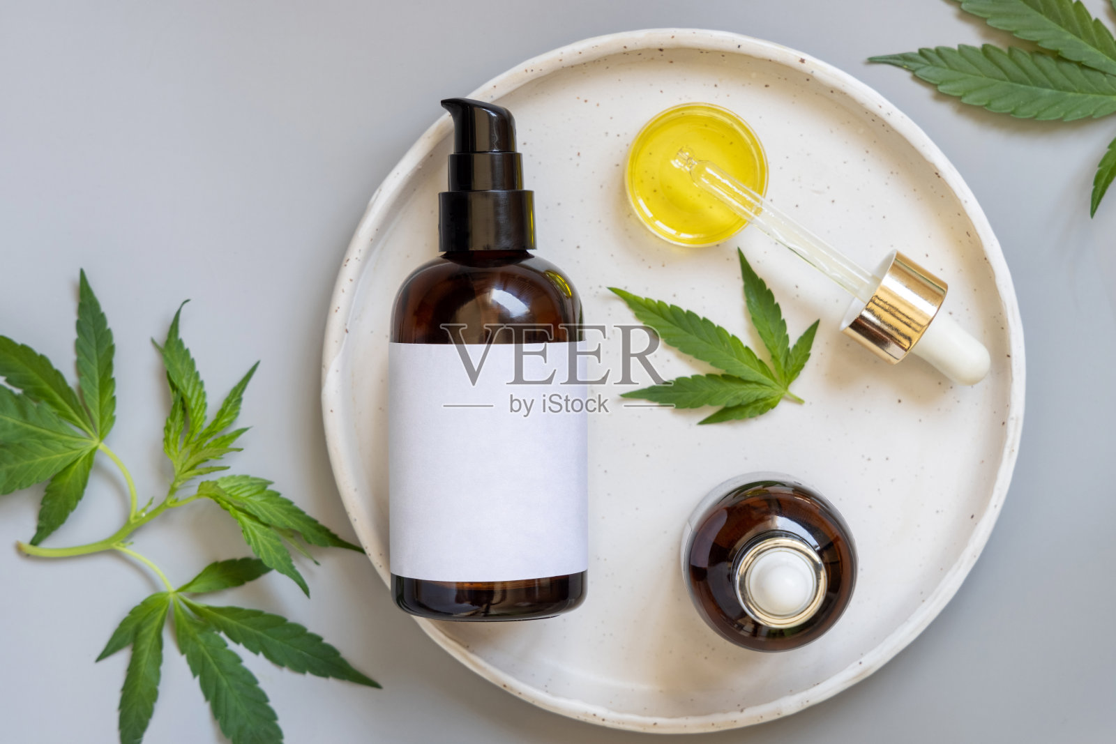 空白化妆品瓶和移液管附近的绿色大麻叶灰色。模型照片摄影图片