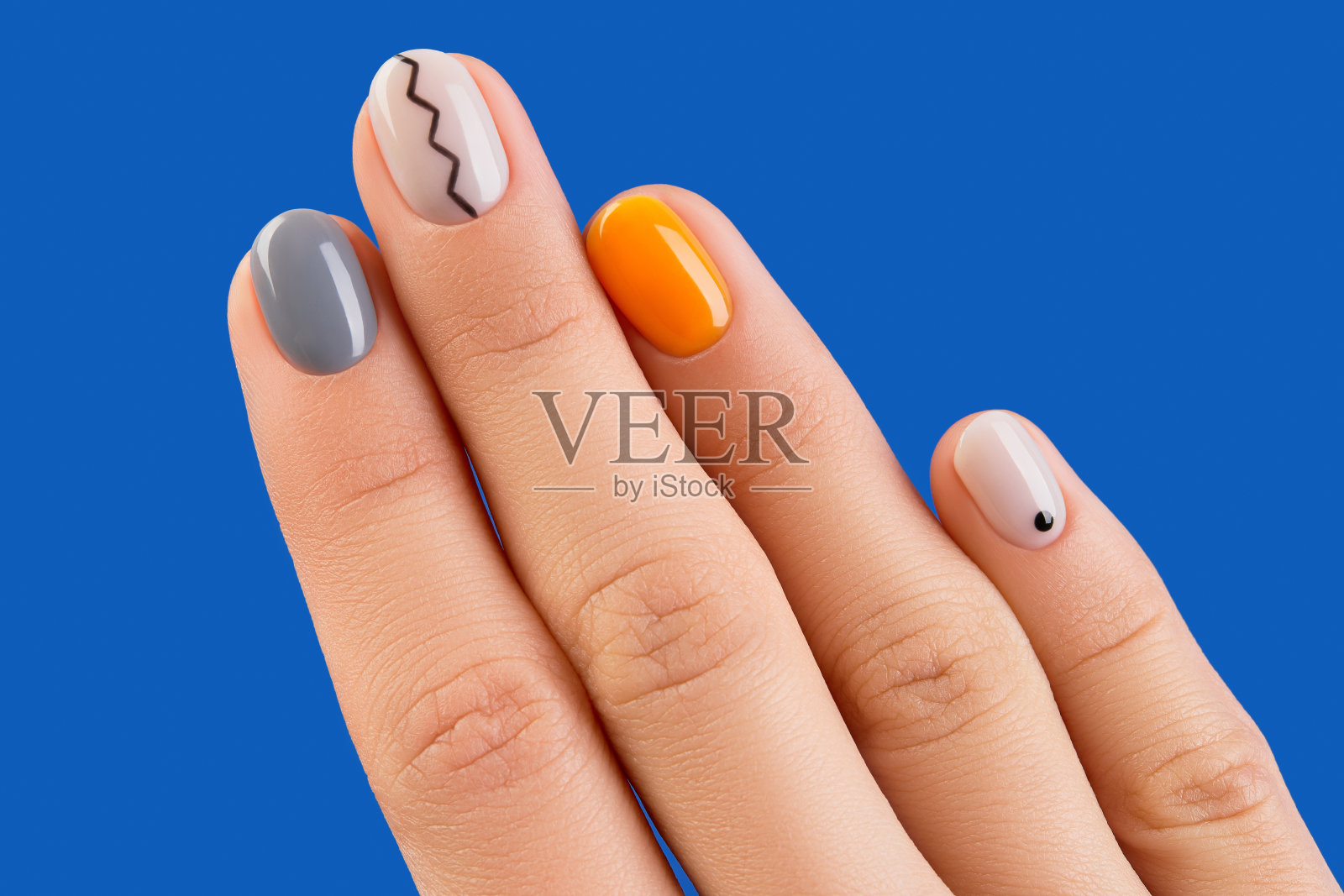 近距离女性的手与时尚的最小的指甲在蓝色背景。秋季美甲设计照片摄影图片