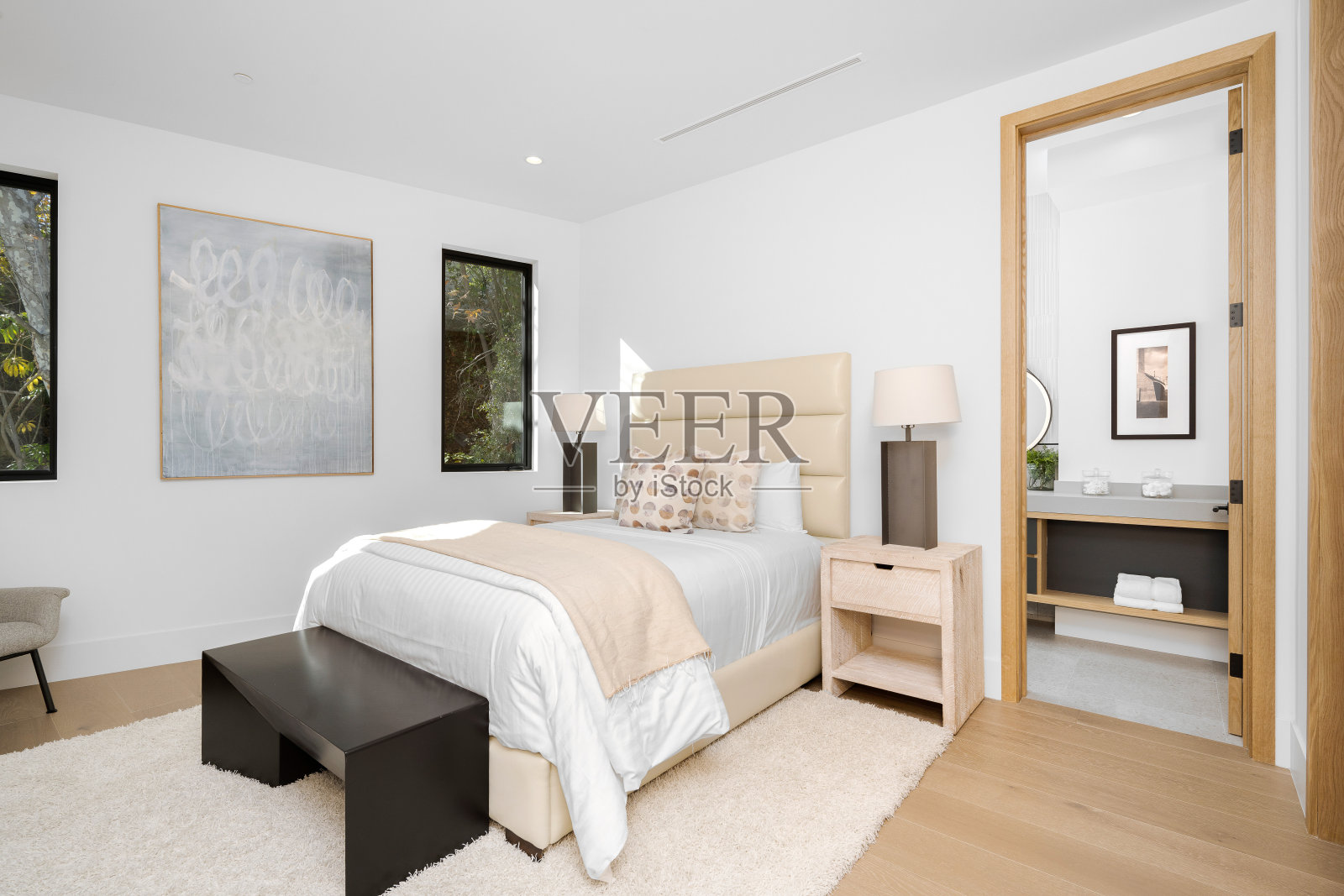 卧室里有一张白色的床和靠窗的梳妆台。照片摄影图片