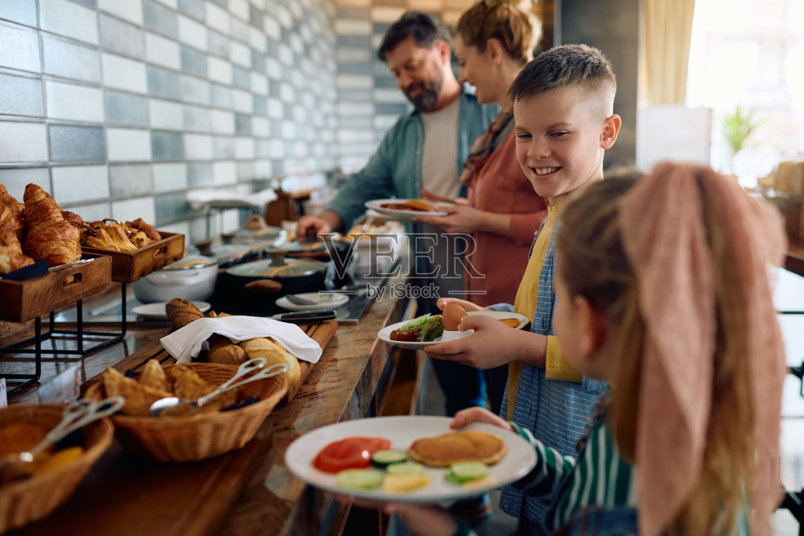 一个快乐的男孩和他的家人在酒店享用早餐。照片摄影图片