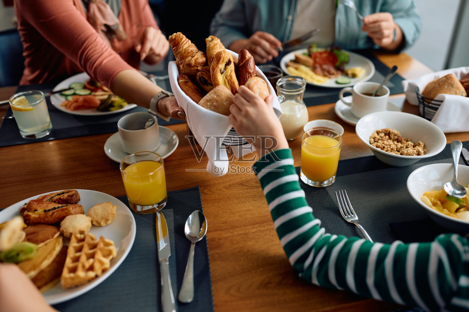 一家人在酒店餐桌上吃早餐的特写。照片摄影图片