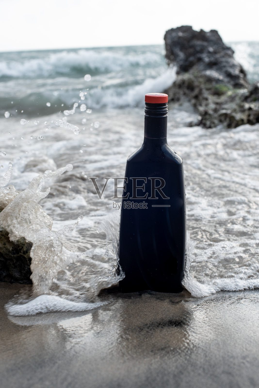 被遗弃在海滩上的黑色瓶子照片摄影图片