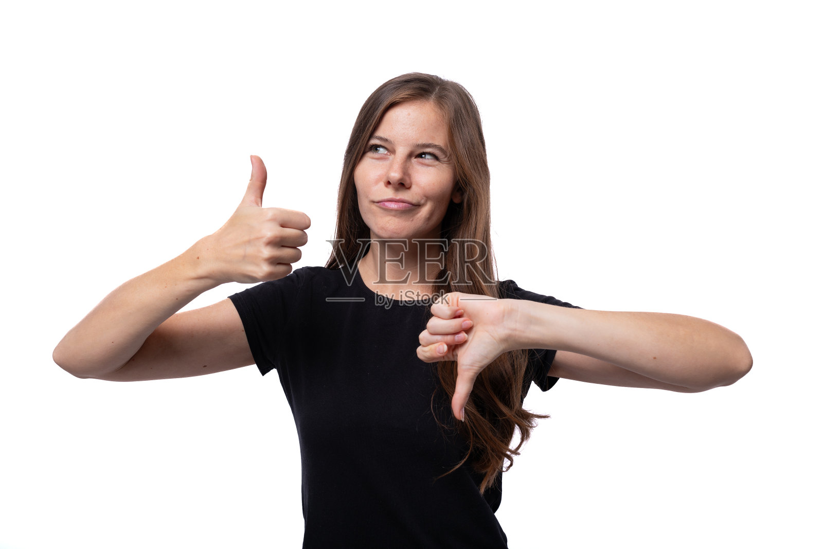 一个年轻漂亮的女人穿着一件基本的t恤，怀疑并表现出喜欢和不喜欢照片摄影图片