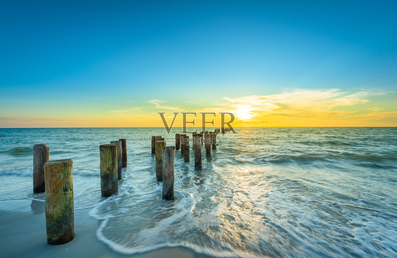 日落时，佛罗里达那不勒斯海滩上的木桩照片摄影图片