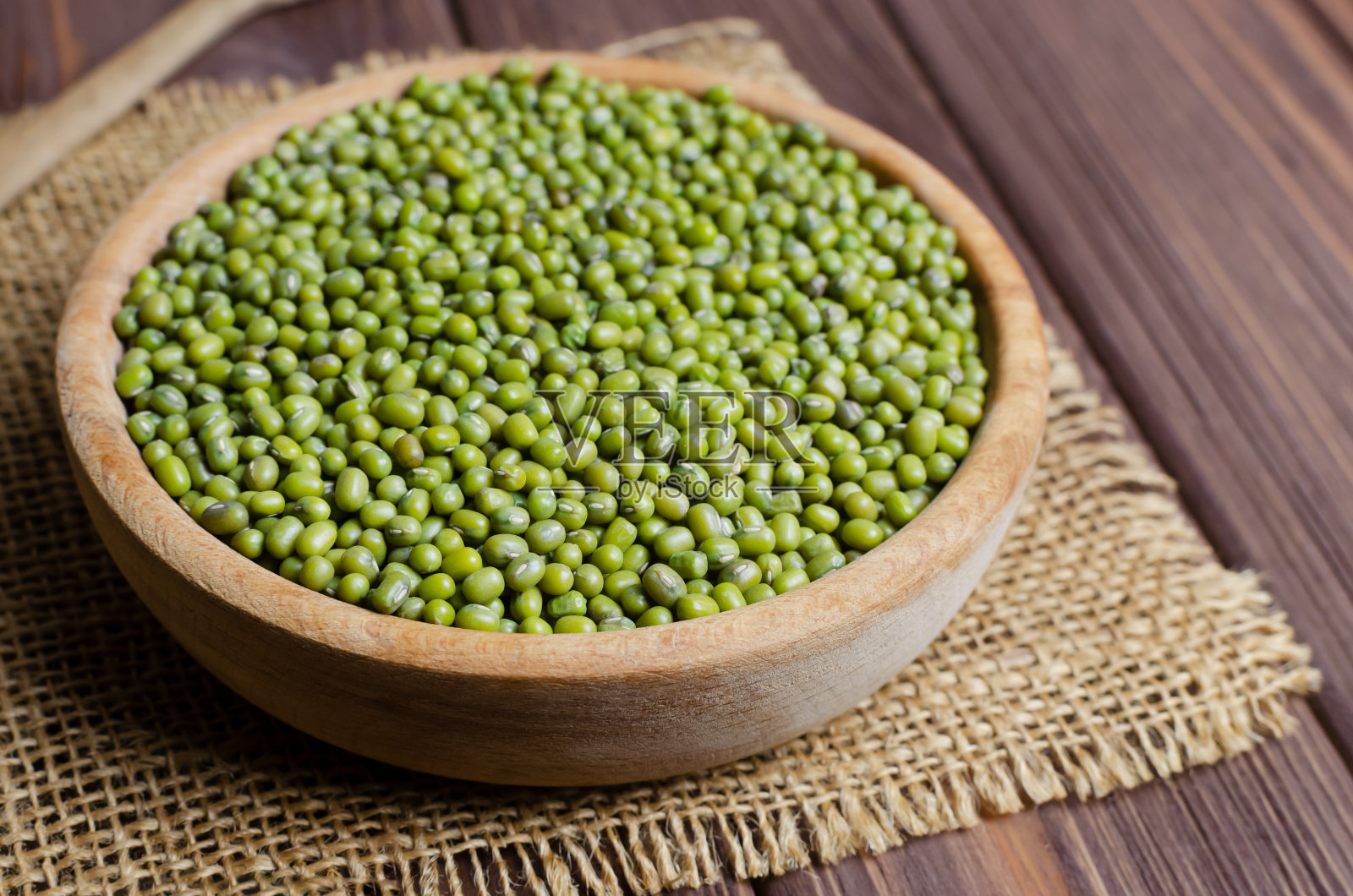 在木桌上的粗麻布上放着一碗绿绿豆。有机豆类。素食主义者和素食食品。乡村风格。健康饮食的概念。水平方向。副本的空间。有选择性的重点。照片摄影图片