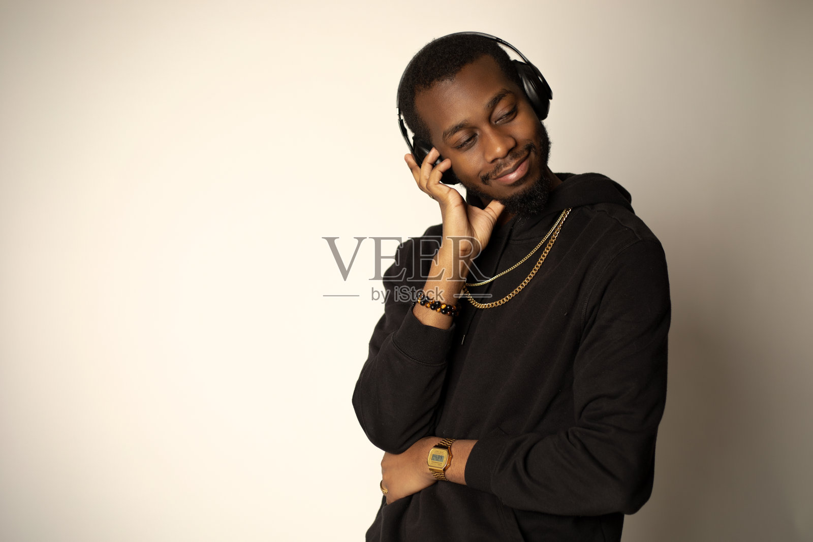 一个戴着耳机的非洲裔美国人，右手捂着脸，左臂搭在肚子上，咧着嘴笑照片摄影图片