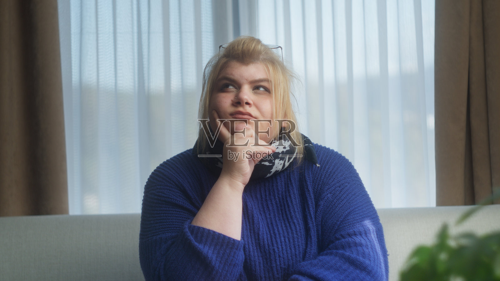 困惑沉思的女人坐在沙发上思考一个主意。女人思虑深梦求解，在家难有创造性的深思照片摄影图片