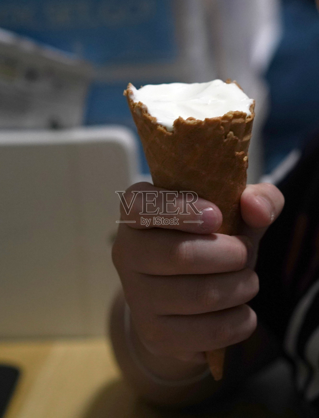 手持冰淇淋威化筒在室内，近距离照片摄影图片