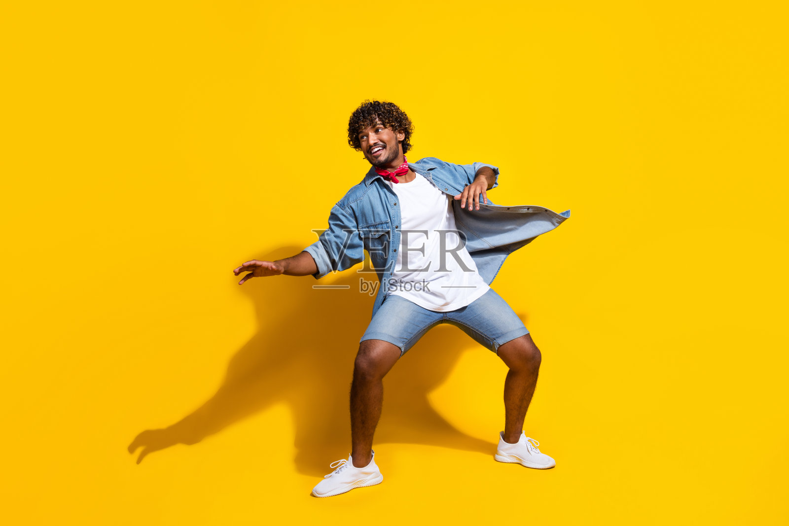 迷人的年轻人冲浪保持平衡的全身照片穿着时尚的牛仔衣服红色围巾孤立在黄色背景照片摄影图片