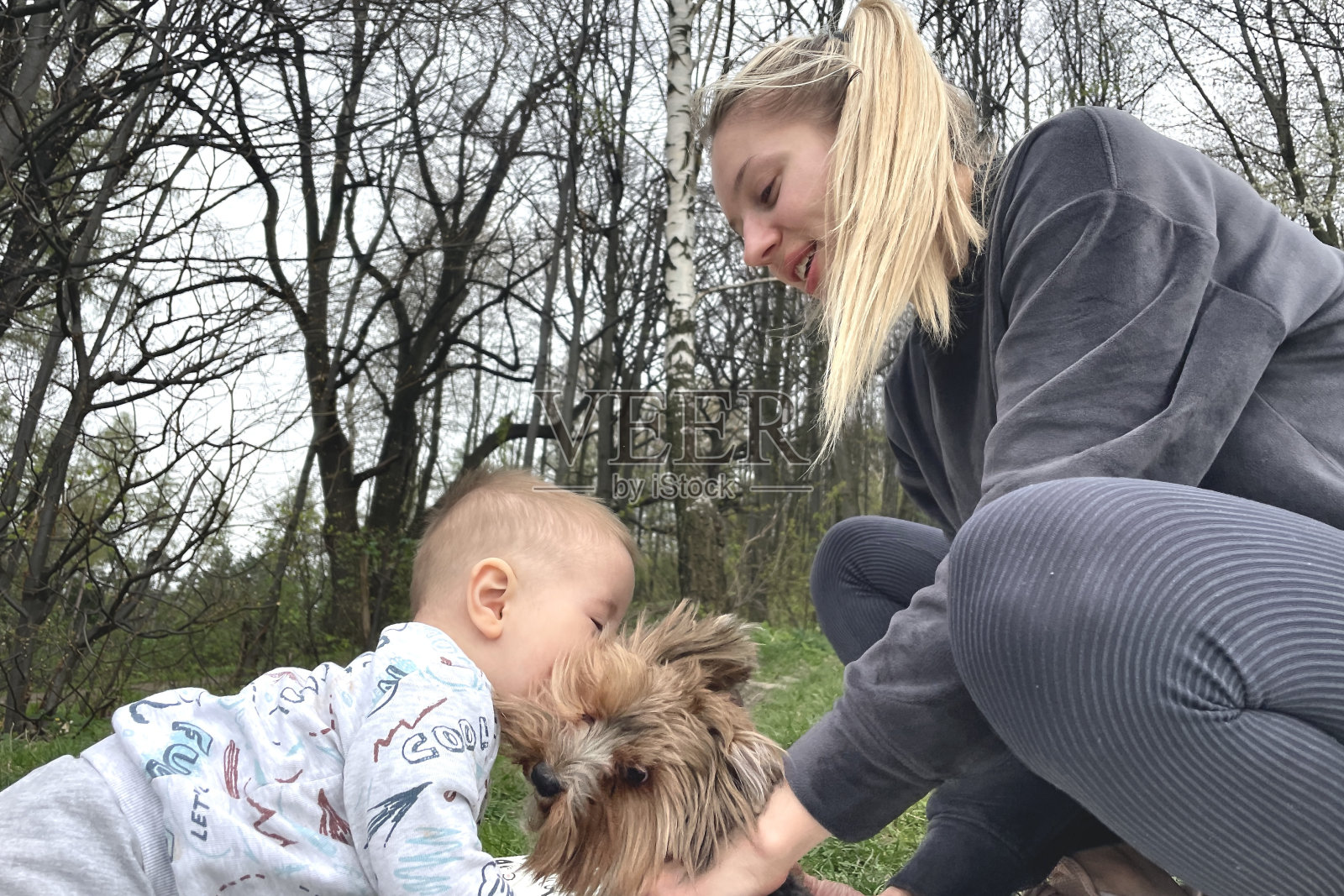 春天的周末，一位母亲带着孩子和一只狗在公园里玩耍照片摄影图片