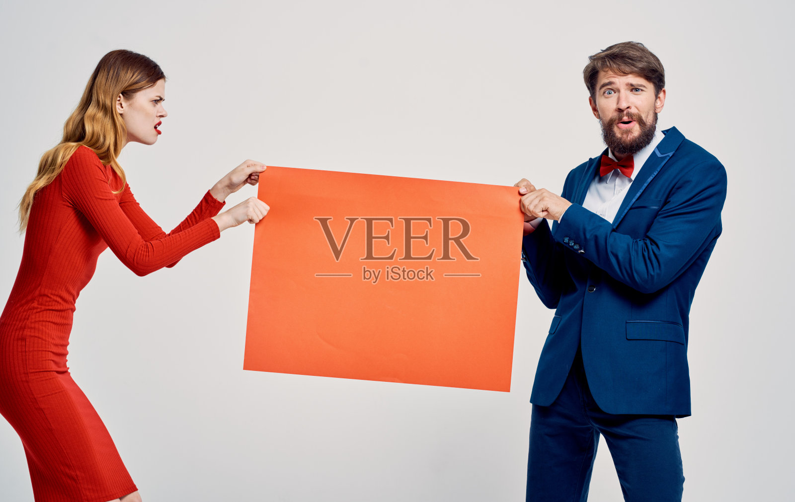 在一个穿着红裙子的女人和一个穿着西装的情绪化的男人的手中模拟照片摄影图片