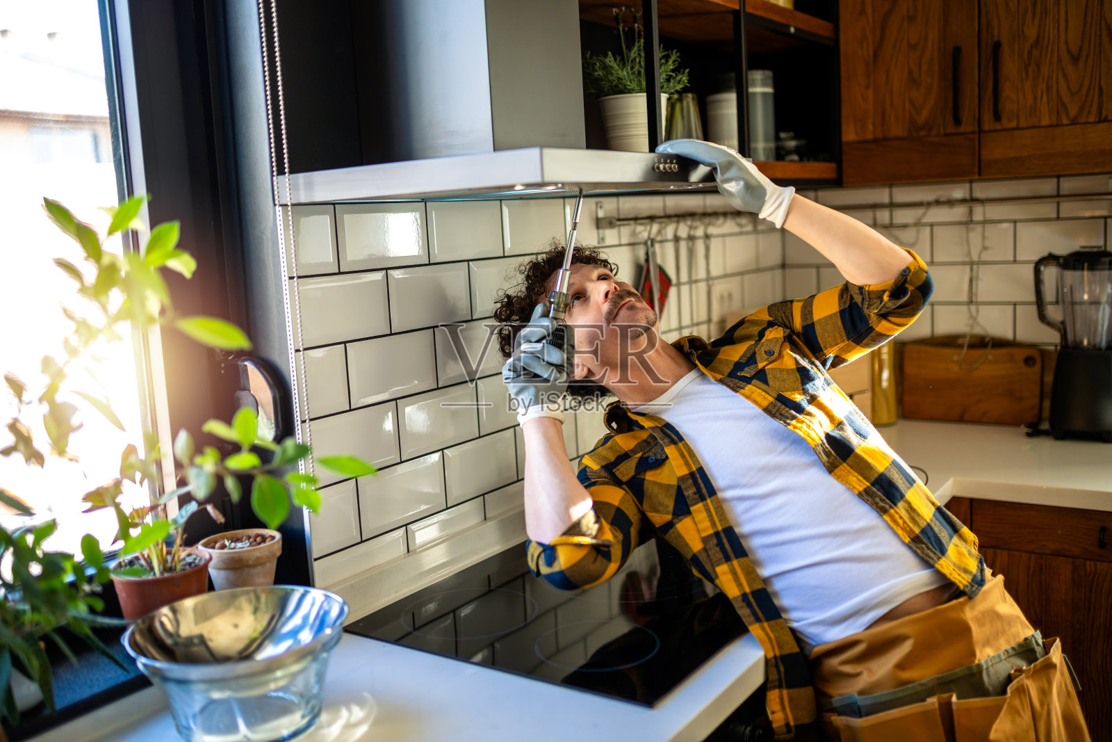 拉丁裔男子在厨房修理吸入器。照片摄影图片