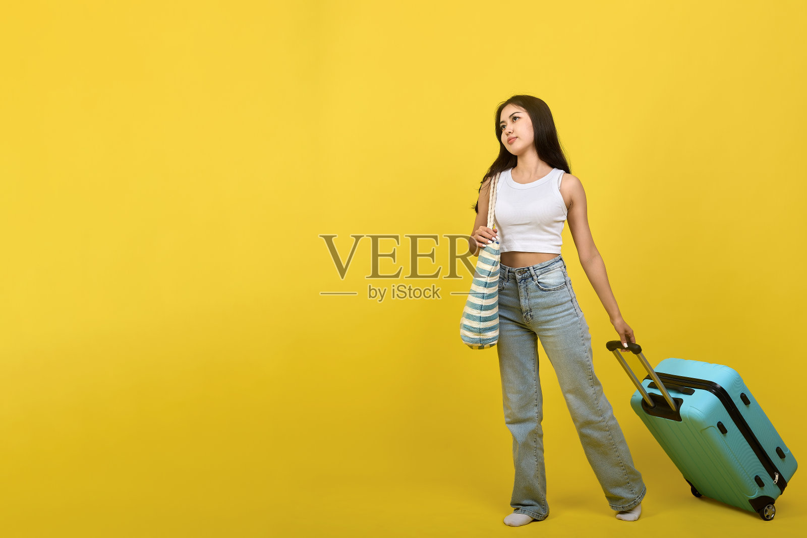 年轻漂亮的女人带着行李若有所思地走着照片摄影图片