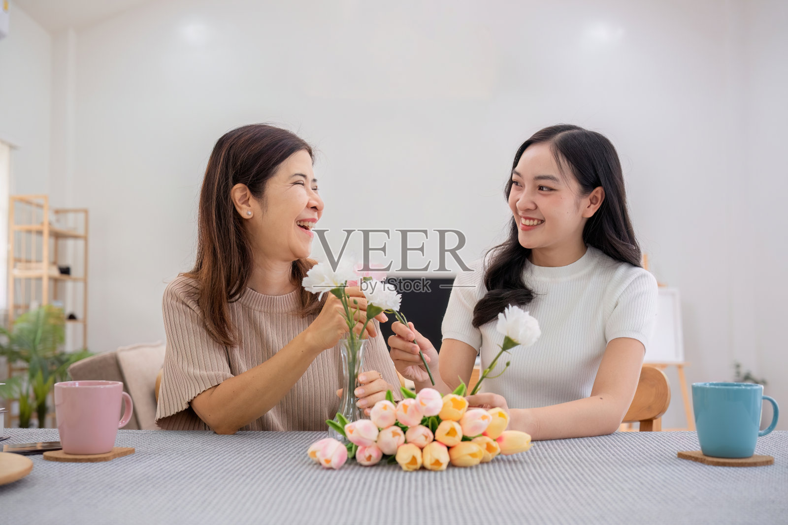 中年女儿在家里和妈妈一起开心地插花，业余时间全家一起做的活动照片摄影图片