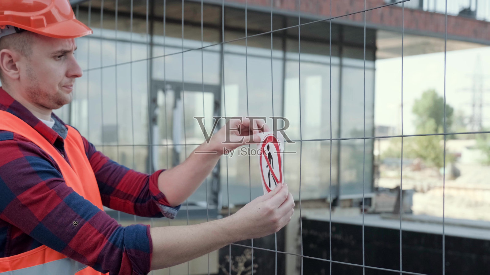 工头在工地的铁链围栏上安装禁止指示牌照片摄影图片