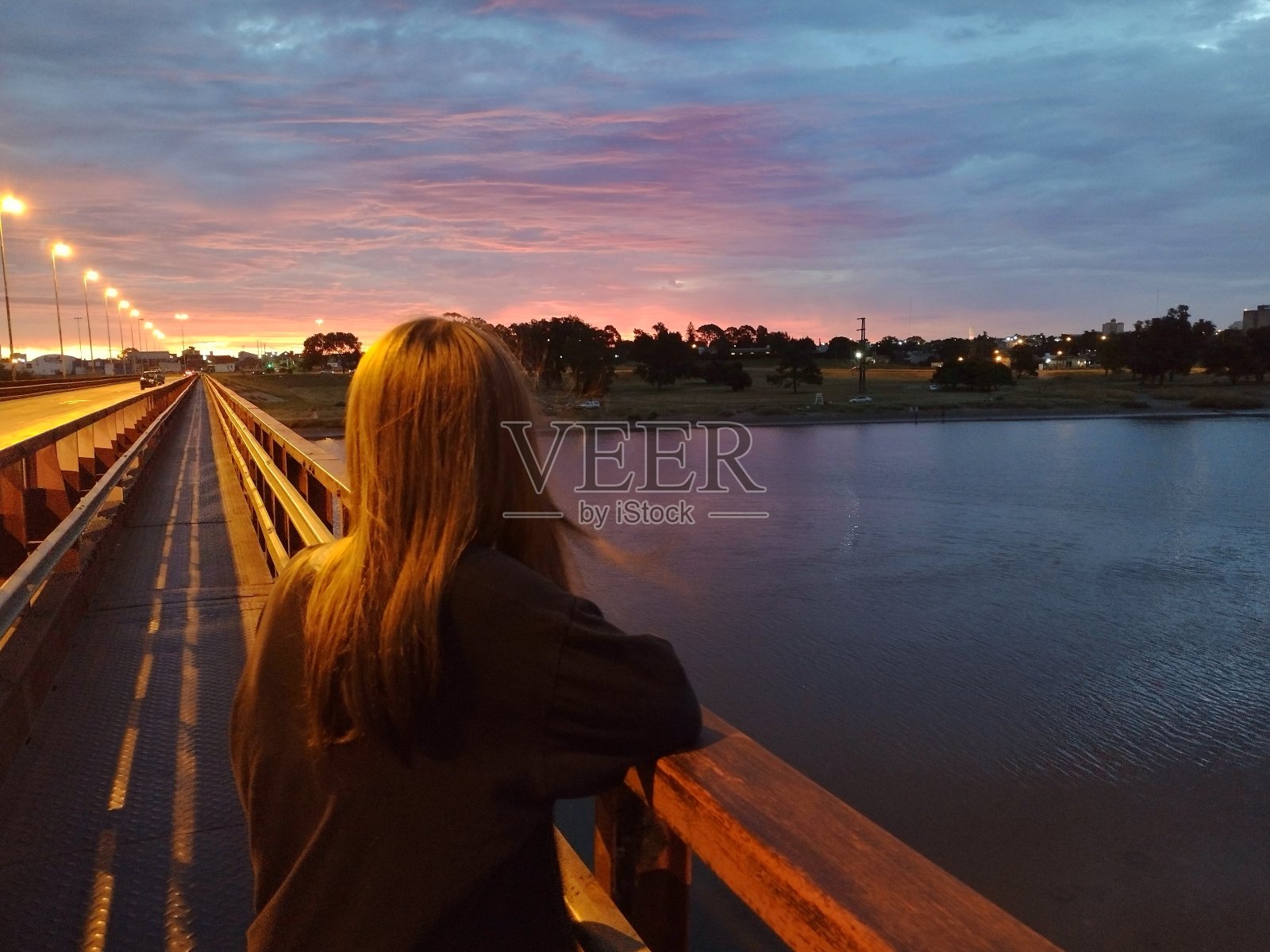 无法辨认的女孩在桥上看日落照片摄影图片