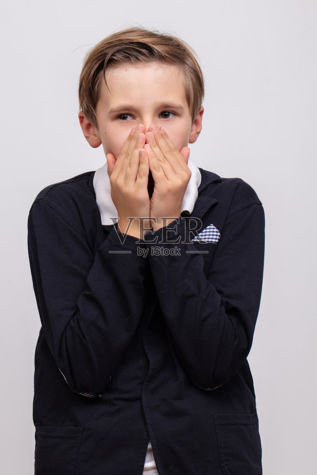 一个十几岁的男孩，一个高中生，用手捂住脸。照片摄影图片