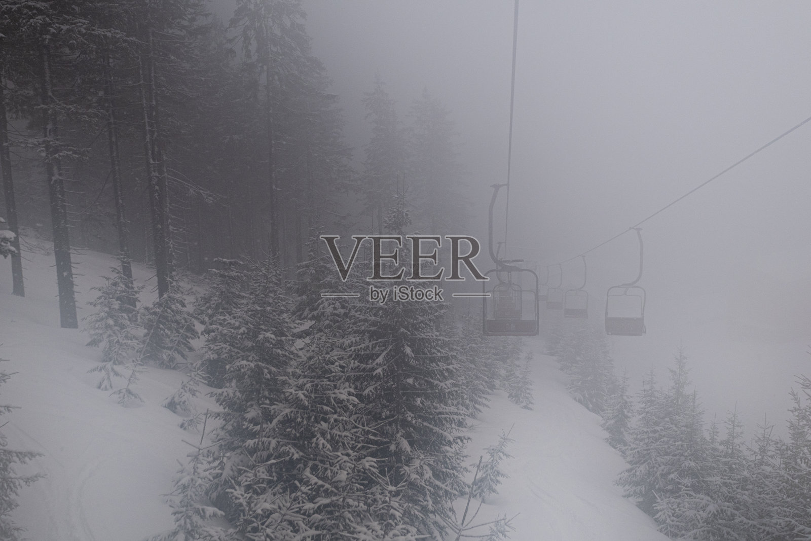 一切都笼罩在浓雾中，但人们继续滑雪，并乘坐缆车爬山照片摄影图片