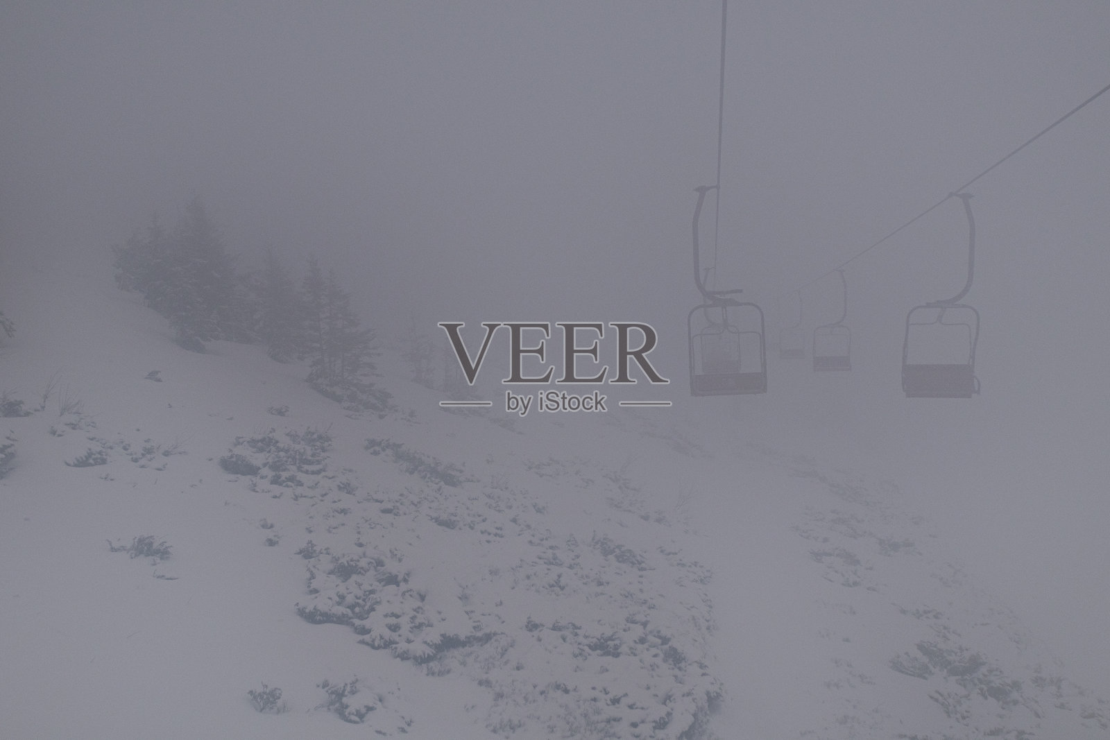 一切都笼罩在浓雾中，但人们继续滑雪，并乘坐缆车爬山照片摄影图片