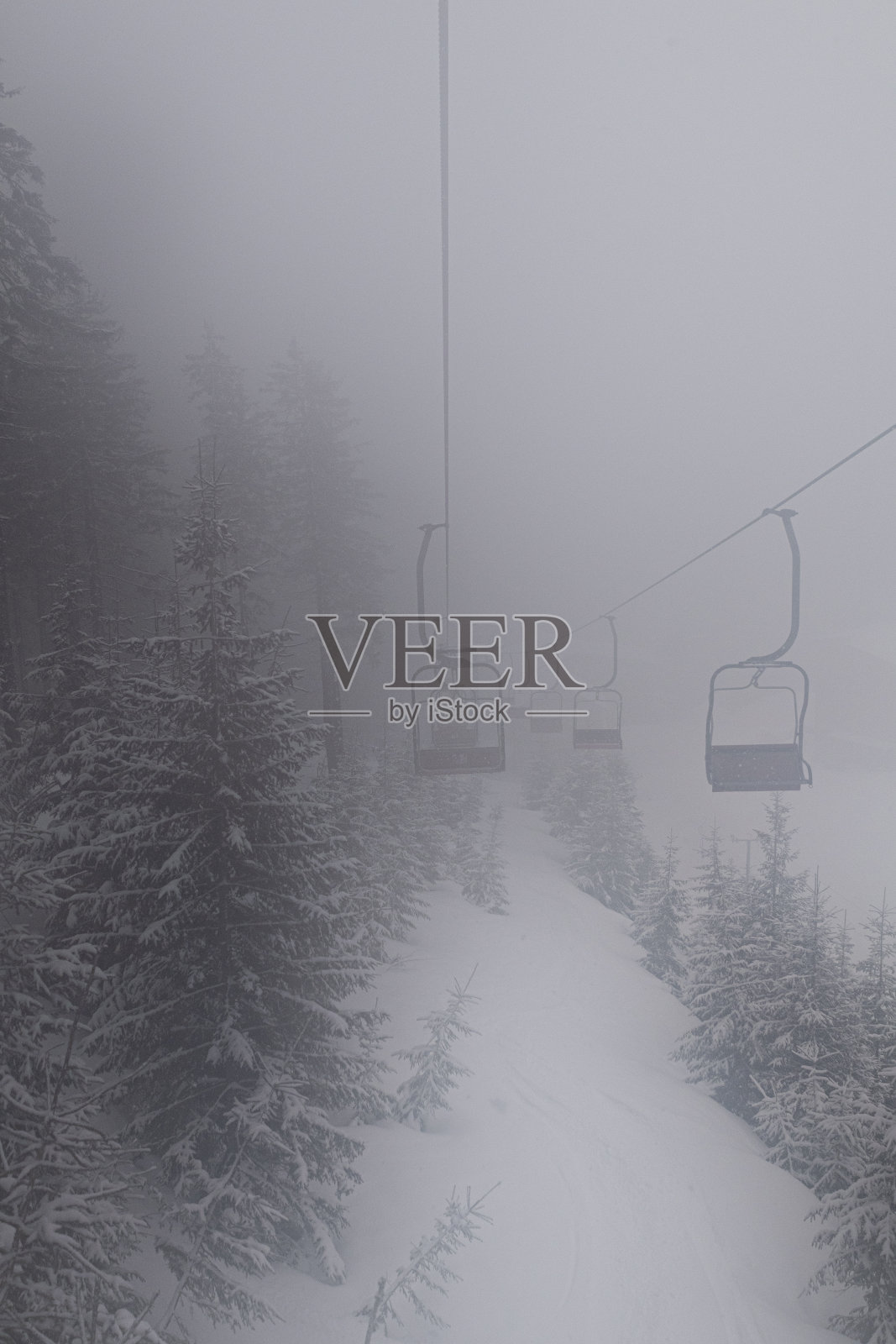 一切都笼罩在浓雾中，但人们继续滑雪，并乘坐缆车爬山照片摄影图片