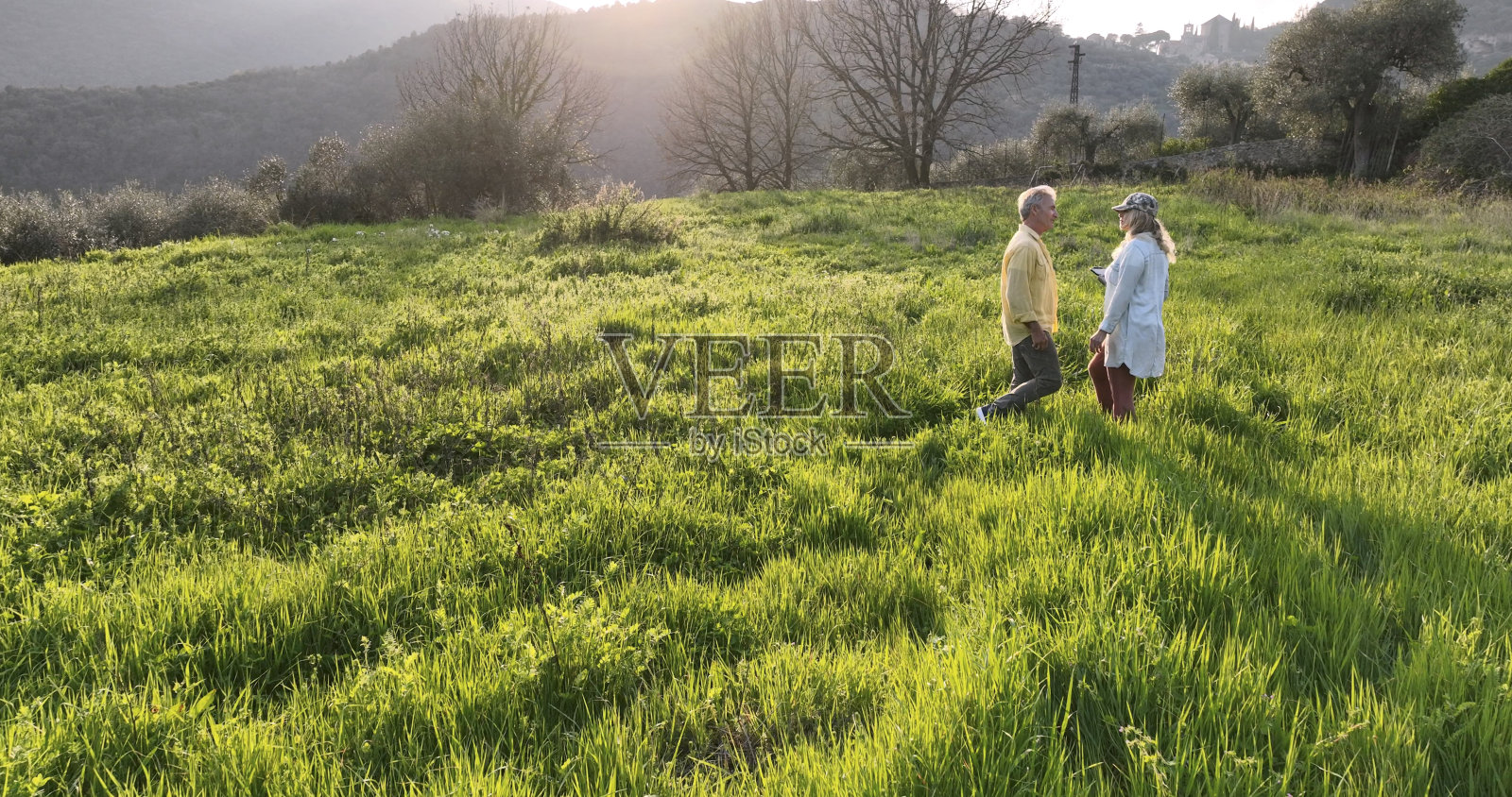 鸟瞰图夫妇在葱郁的草地在日落照片摄影图片