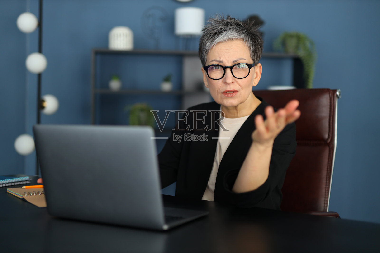 在办公室里，一位紧张的白人女商人在笔记本电脑上解决问题，应对工作中的挑战。照片摄影图片