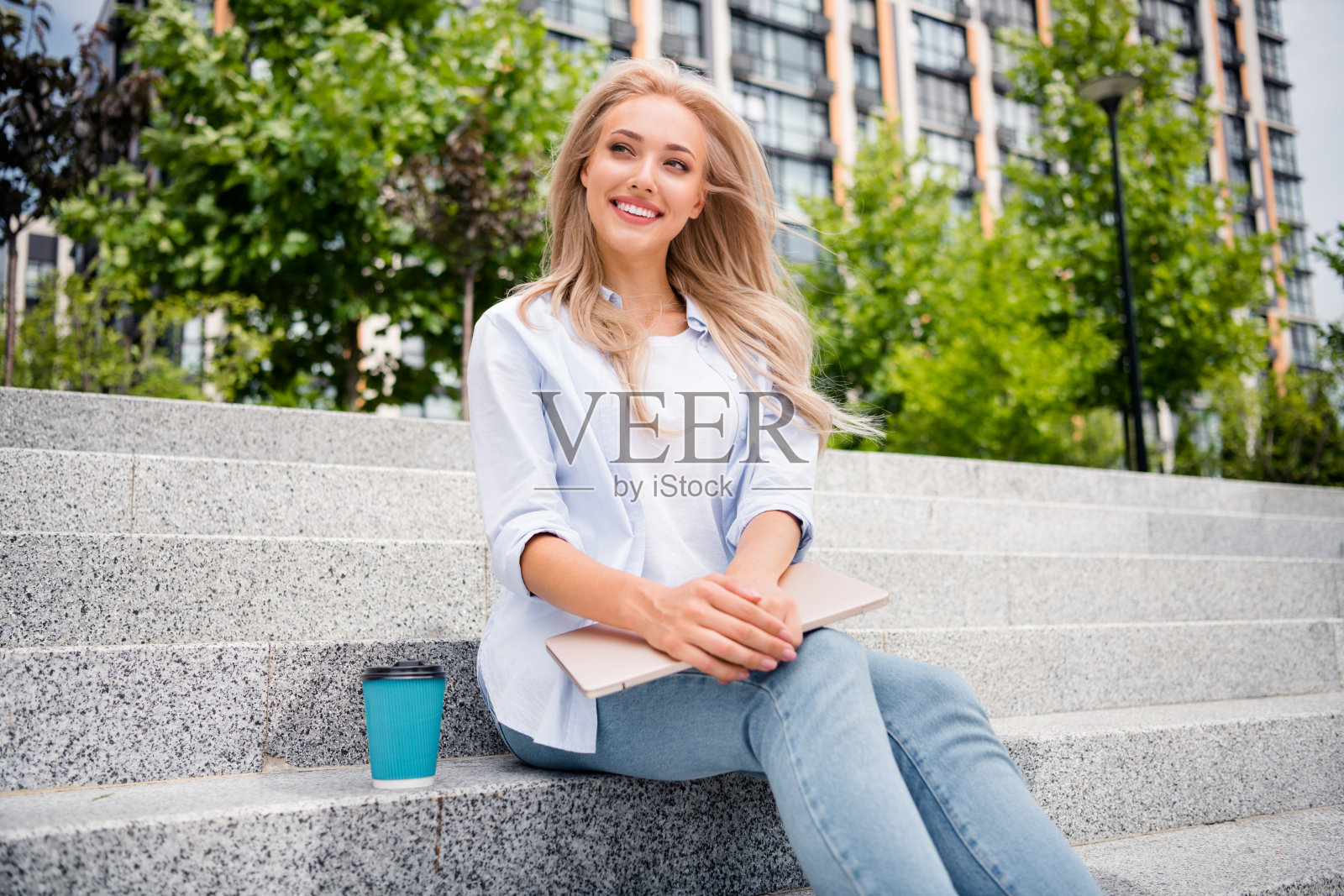 有思想有吸引力的年轻金发卷发的照片年轻的女员工在户外喝咖啡休息与上网本坐在楼梯照片摄影图片