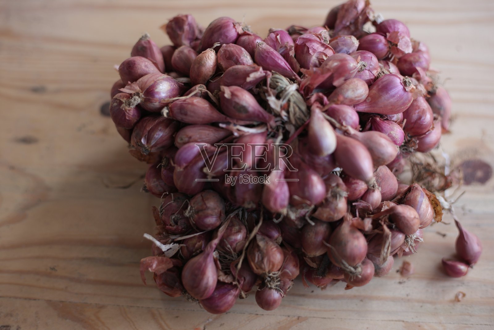 鲜红葱葱巴旺美拉在木背景上分离而健康，选择性聚焦。照片摄影图片