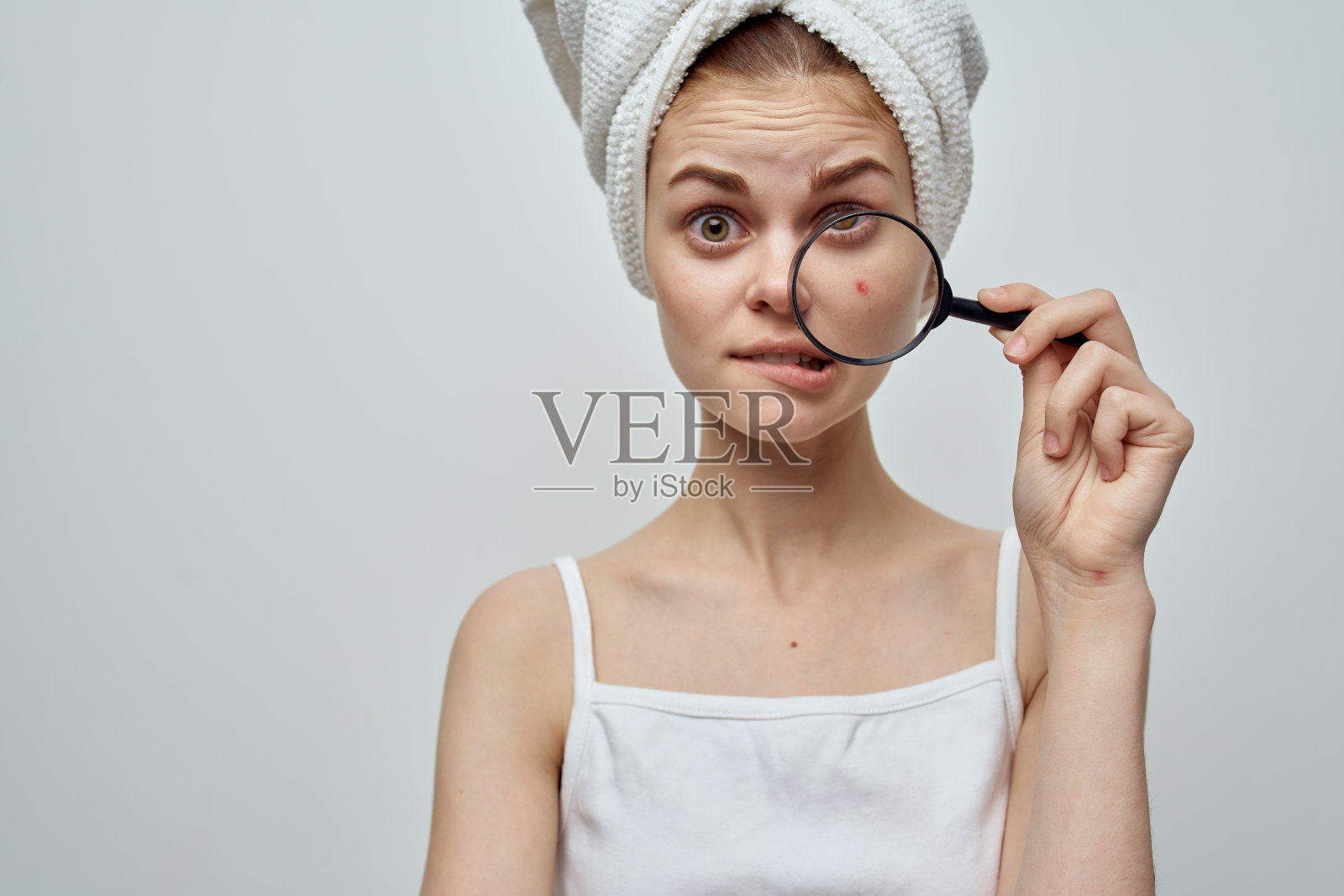 一个漂亮的女人，头上裹着毛巾，手里拿着放大镜，脸上长着粉刺照片摄影图片