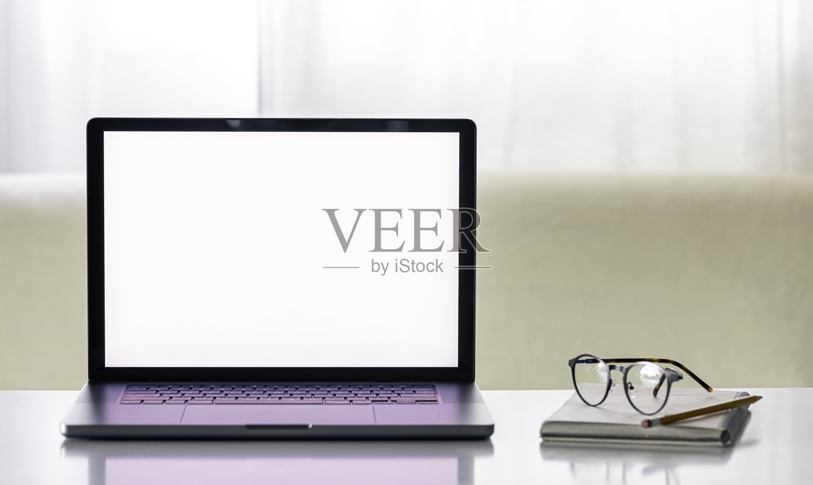 白色的桌子上放着一台空白屏幕的笔记本电脑，还有记事本和眼镜。照片摄影图片