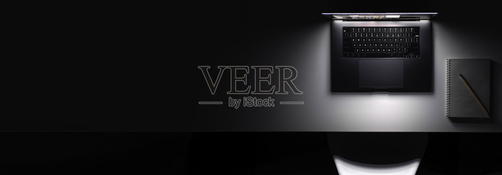 有发光屏幕的笔记本电脑放在黑暗的桌子上，俯视图，复印空间。照片摄影图片