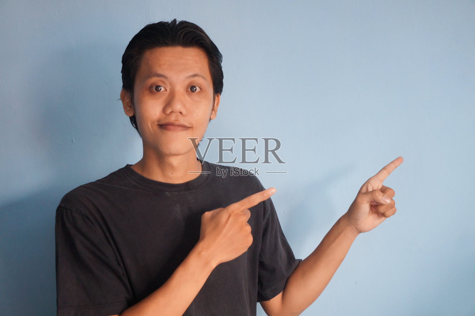 穿着黑色t恤的年轻亚洲男子做欢迎的手势或介绍照片摄影图片